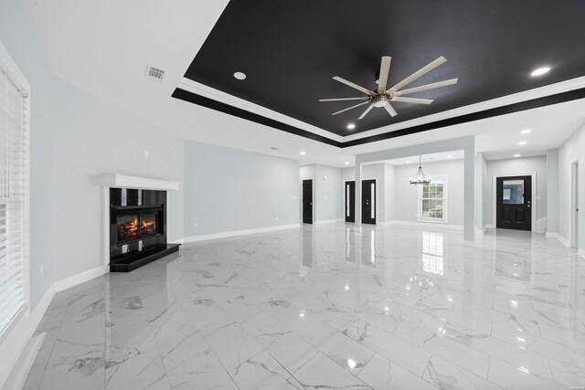 unfurnished living room with marble finish floor, a glass covered fireplace, a raised ceiling, and baseboards