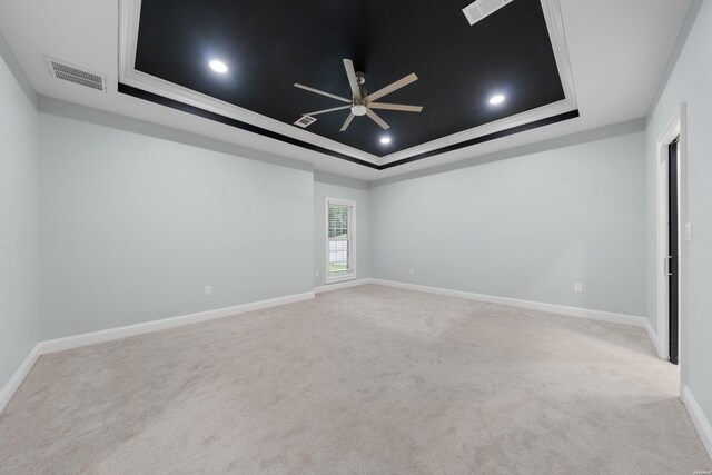 unfurnished room featuring a tray ceiling, light colored carpet, ceiling fan, and baseboards