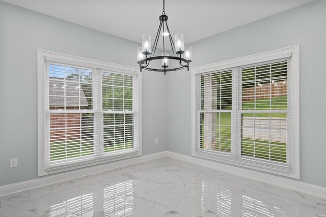 unfurnished dining area featuring marble finish floor, a wealth of natural light, and baseboards