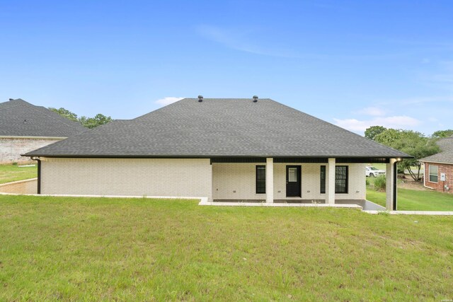 back of house featuring a patio area, roof with shingles, a yard, and brick siding