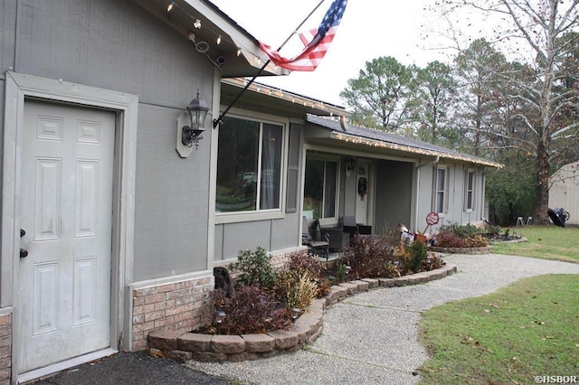 doorway to property with a yard and brick siding