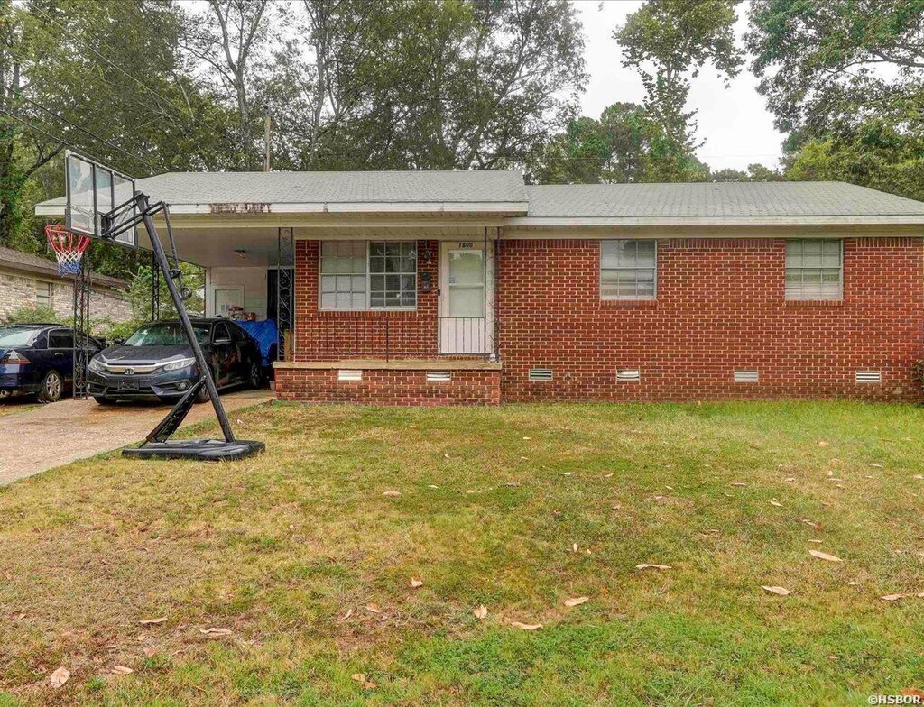 ranch-style home with brick siding, a front yard, crawl space, an attached carport, and driveway