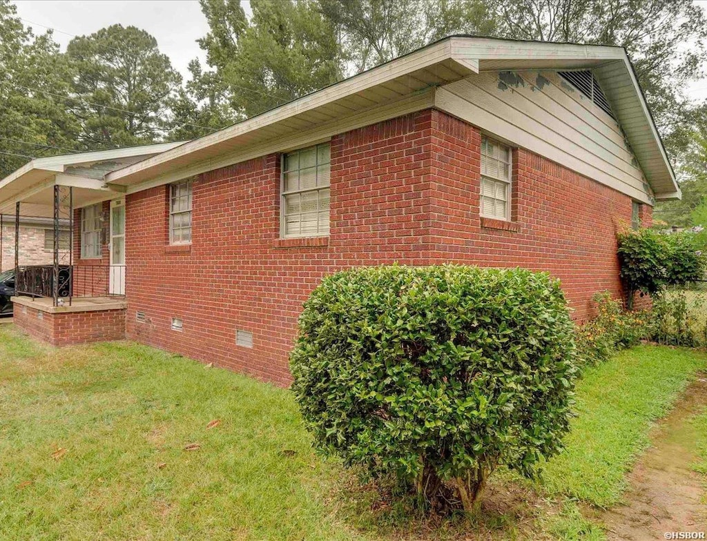 view of home's exterior with brick siding, crawl space, and a lawn