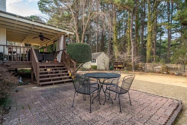 view of patio / terrace with ceiling fan, a deck, outdoor dining area, an outdoor structure, and fence