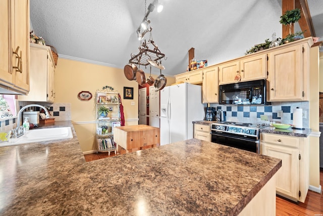 kitchen featuring white refrigerator with ice dispenser, range, dark countertops, black microwave, and a sink