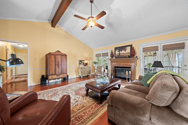 living area with lofted ceiling with beams, ceiling fan, a fireplace, wood finished floors, and baseboards