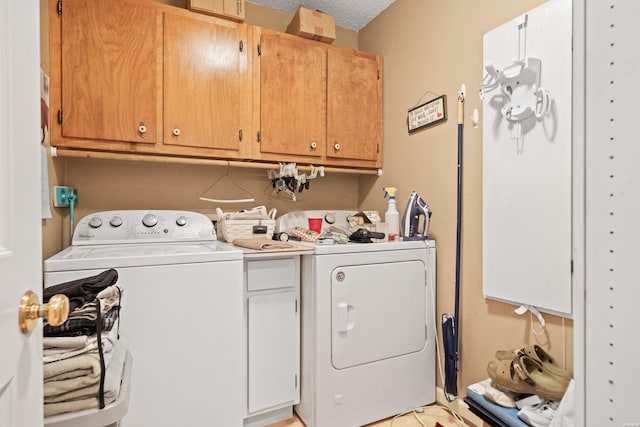 clothes washing area with a textured ceiling, separate washer and dryer, and cabinet space