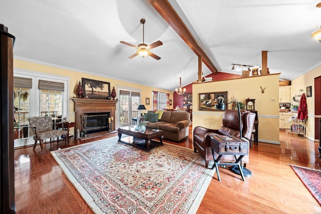 living room with crown molding, a fireplace, light wood-style flooring, lofted ceiling with beams, and a textured ceiling