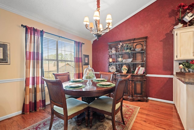 dining space with lofted ceiling, light wood-style flooring, a notable chandelier, baseboards, and ornamental molding