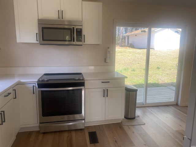 kitchen with visible vents, appliances with stainless steel finishes, white cabinets, and light countertops