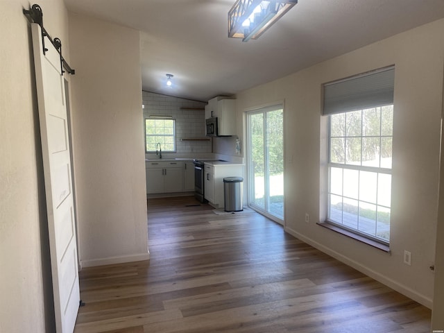 kitchen featuring lofted ceiling, stainless steel microwave, electric range oven, a barn door, and wood finished floors