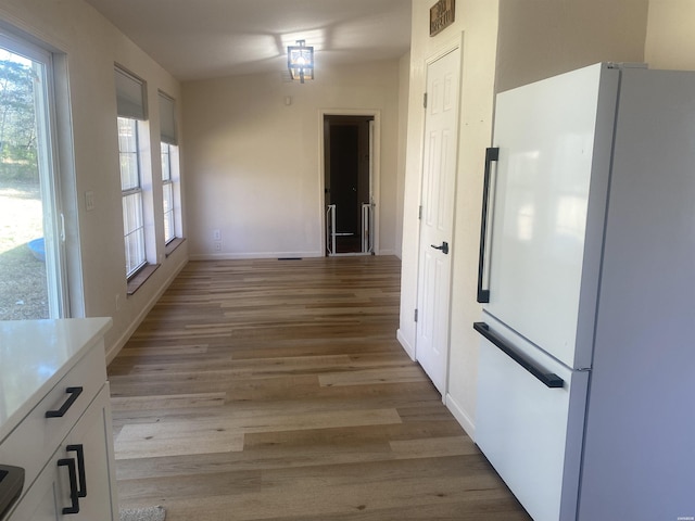 kitchen featuring white cabinetry, baseboards, light countertops, light wood-type flooring, and freestanding refrigerator