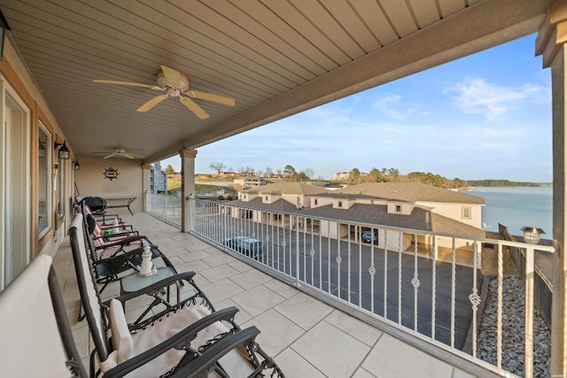 view of patio with a water view, a balcony, and a ceiling fan