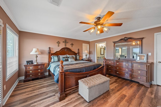 bedroom featuring visible vents, ensuite bathroom, wood finished floors, crown molding, and baseboards