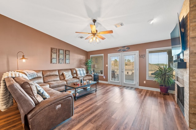 living room with visible vents, lofted ceiling, a fireplace, french doors, and wood finished floors