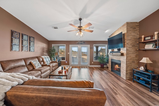 living area with french doors, a large fireplace, wood finished floors, and vaulted ceiling