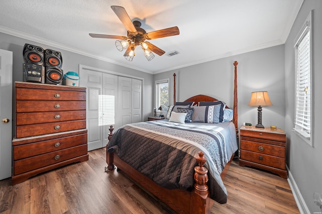 bedroom with crown molding, wood finished floors, and visible vents