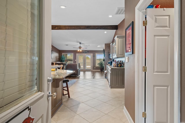 interior space with light tile patterned floors, visible vents, baseboards, beam ceiling, and french doors