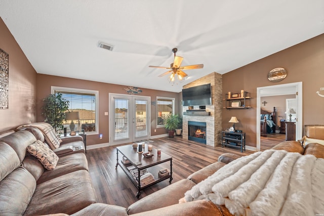 living room featuring visible vents, lofted ceiling, a stone fireplace, french doors, and wood finished floors