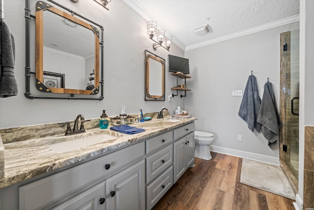 bathroom featuring visible vents, a sink, wood finished floors, and ornamental molding