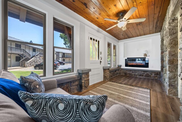 interior space with a healthy amount of sunlight, wood ceiling, wood finished floors, and a glass covered fireplace