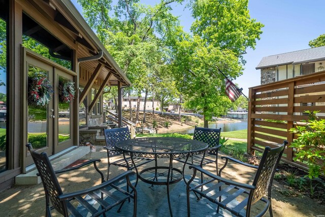 view of patio / terrace featuring entry steps, french doors, a water view, and outdoor dining space