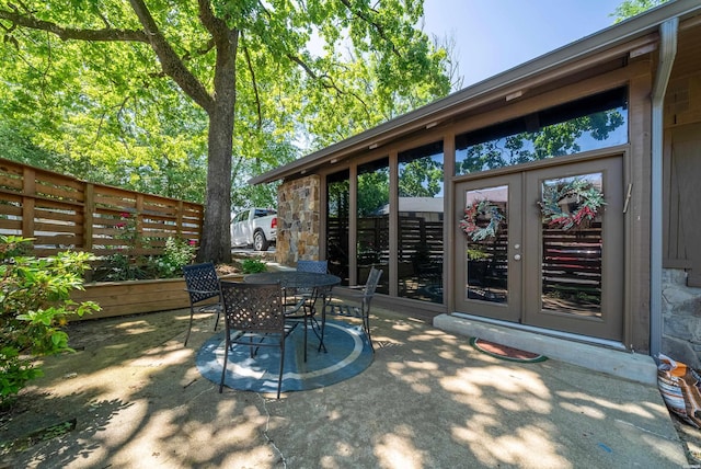 view of patio featuring french doors, outdoor dining area, and fence