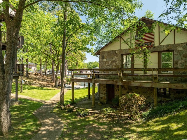 rear view of property with stone siding, a deck, a lawn, and stucco siding