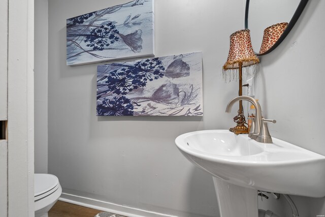 bathroom featuring toilet, baseboards, a sink, and wood finished floors