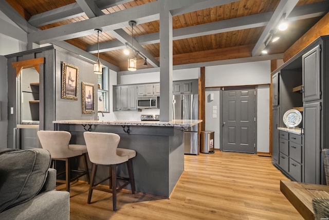 kitchen featuring a peninsula, stainless steel appliances, light stone counters, and gray cabinets