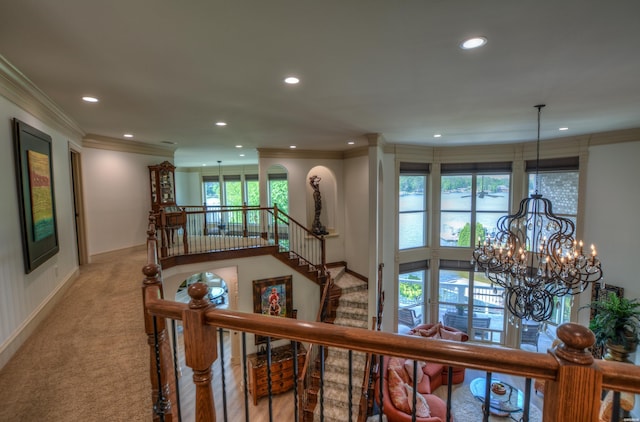 hallway featuring an upstairs landing, a chandelier, crown molding, and light colored carpet