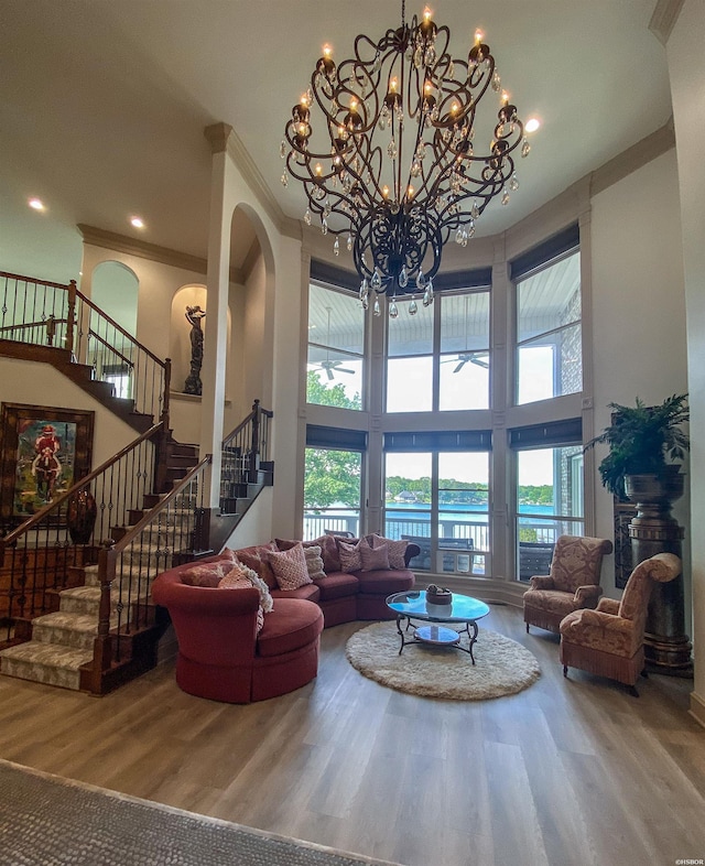 living area featuring stairway, plenty of natural light, wood finished floors, and a towering ceiling