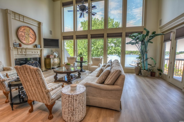 living room with a wealth of natural light, a towering ceiling, and wood finished floors