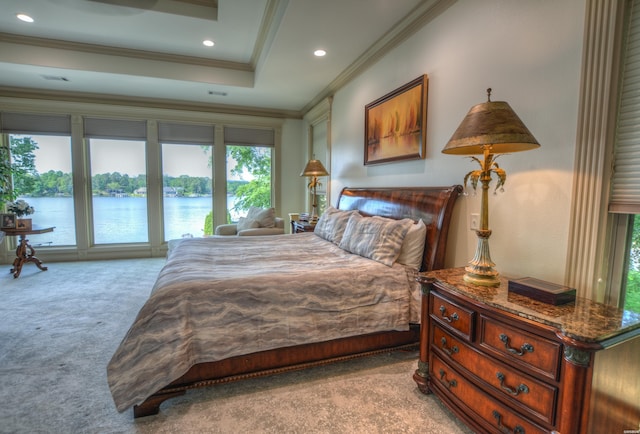 bedroom with a tray ceiling, crown molding, recessed lighting, light colored carpet, and a water view