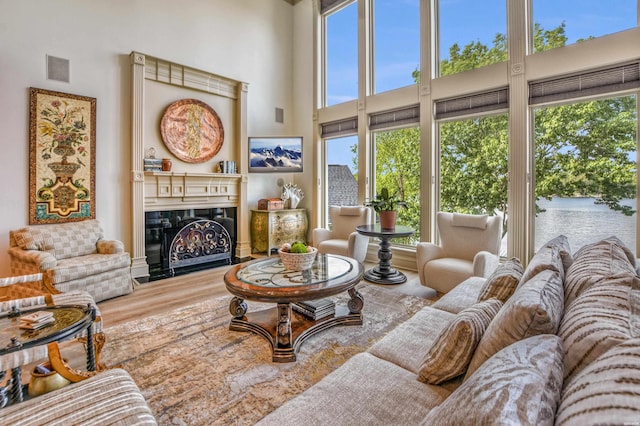 living room with a high ceiling, a fireplace, wood finished floors, and visible vents