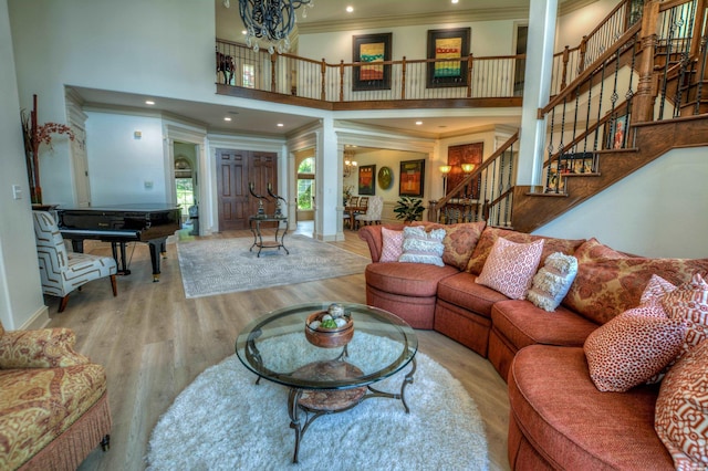 living room featuring crown molding, a notable chandelier, a high ceiling, wood finished floors, and stairs