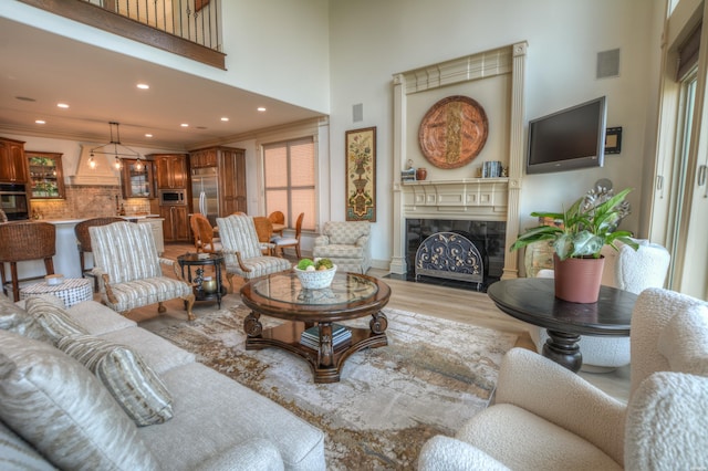 living room with light wood finished floors, a tiled fireplace, visible vents, and crown molding