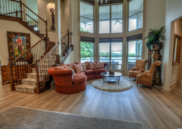 living room with a high ceiling, stairway, wood finished floors, and baseboards