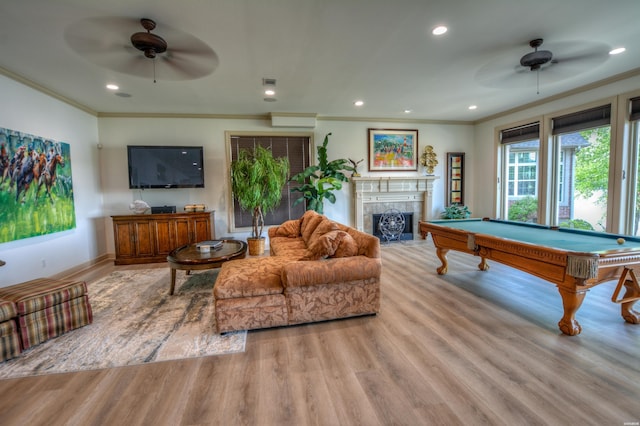 rec room featuring a high end fireplace, ceiling fan, ornamental molding, light wood-style floors, and recessed lighting