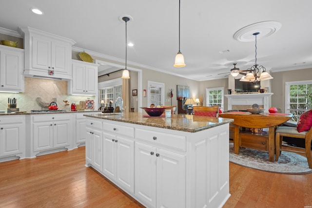 kitchen featuring dark stone countertops, a kitchen island, decorative light fixtures, and white cabinets