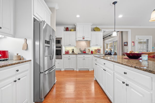 kitchen with decorative light fixtures, appliances with stainless steel finishes, white cabinets, a sink, and dark stone countertops