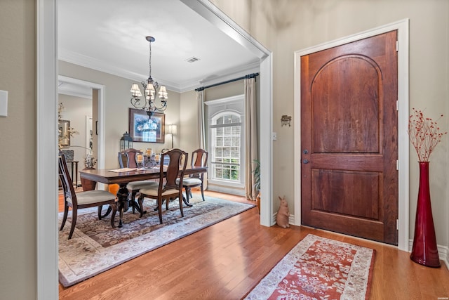 dining area featuring a notable chandelier, visible vents, ornamental molding, and wood finished floors