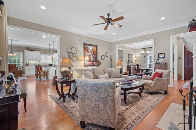 living area featuring crown molding, recessed lighting, ceiling fan with notable chandelier, and light wood-style floors