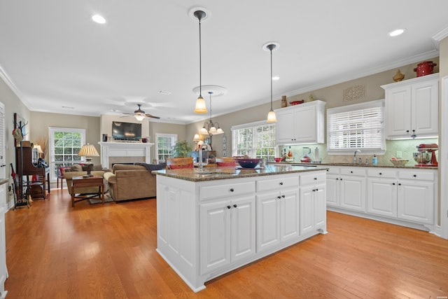 kitchen featuring hanging light fixtures, a kitchen island, white cabinetry, and a tile fireplace