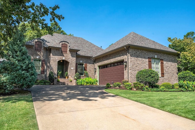 french provincial home featuring driveway, a shingled roof, a garage, and a front lawn