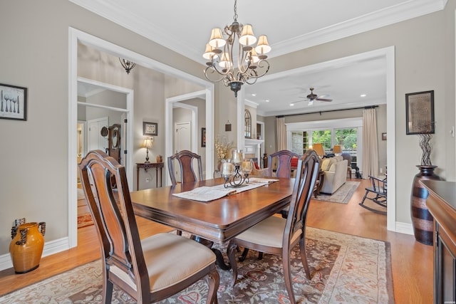 dining room featuring light wood finished floors, ornamental molding, ceiling fan with notable chandelier, and baseboards