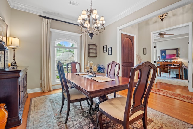 dining room with light wood finished floors, visible vents, baseboards, ornamental molding, and ceiling fan with notable chandelier