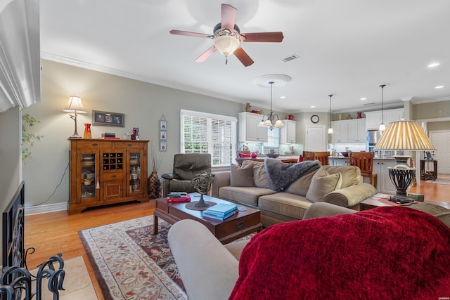 living area with ceiling fan, recessed lighting, visible vents, light wood-type flooring, and crown molding