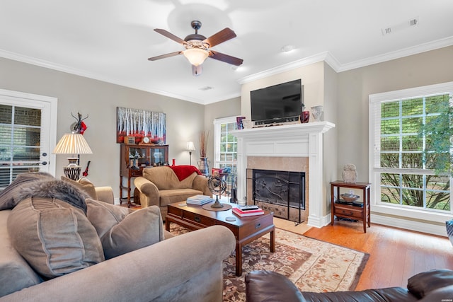 living area featuring light wood-style floors, a fireplace with flush hearth, visible vents, and crown molding