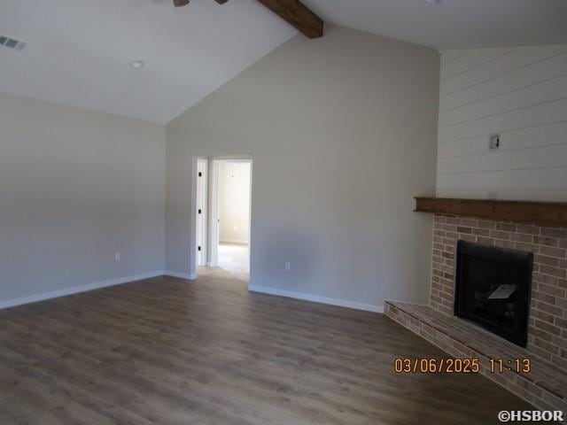 unfurnished living room with wood finished floors, visible vents, baseboards, a brick fireplace, and beam ceiling